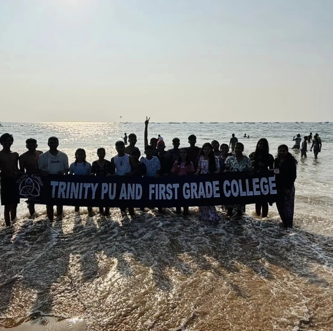 Trinity students holding the college banner on a beach during a study trip